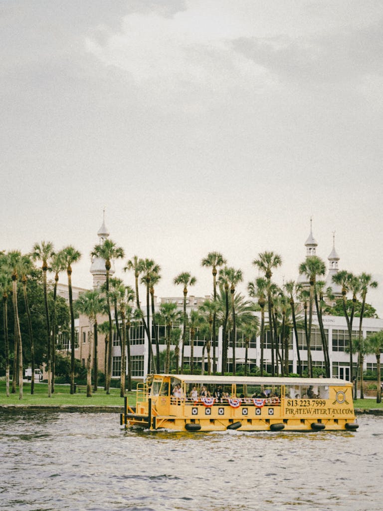 A ferry boat glides on the river with the University of Tampa in the background.