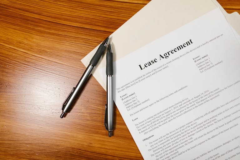 High-angle view of a lease agreement and pens on a wooden desk.